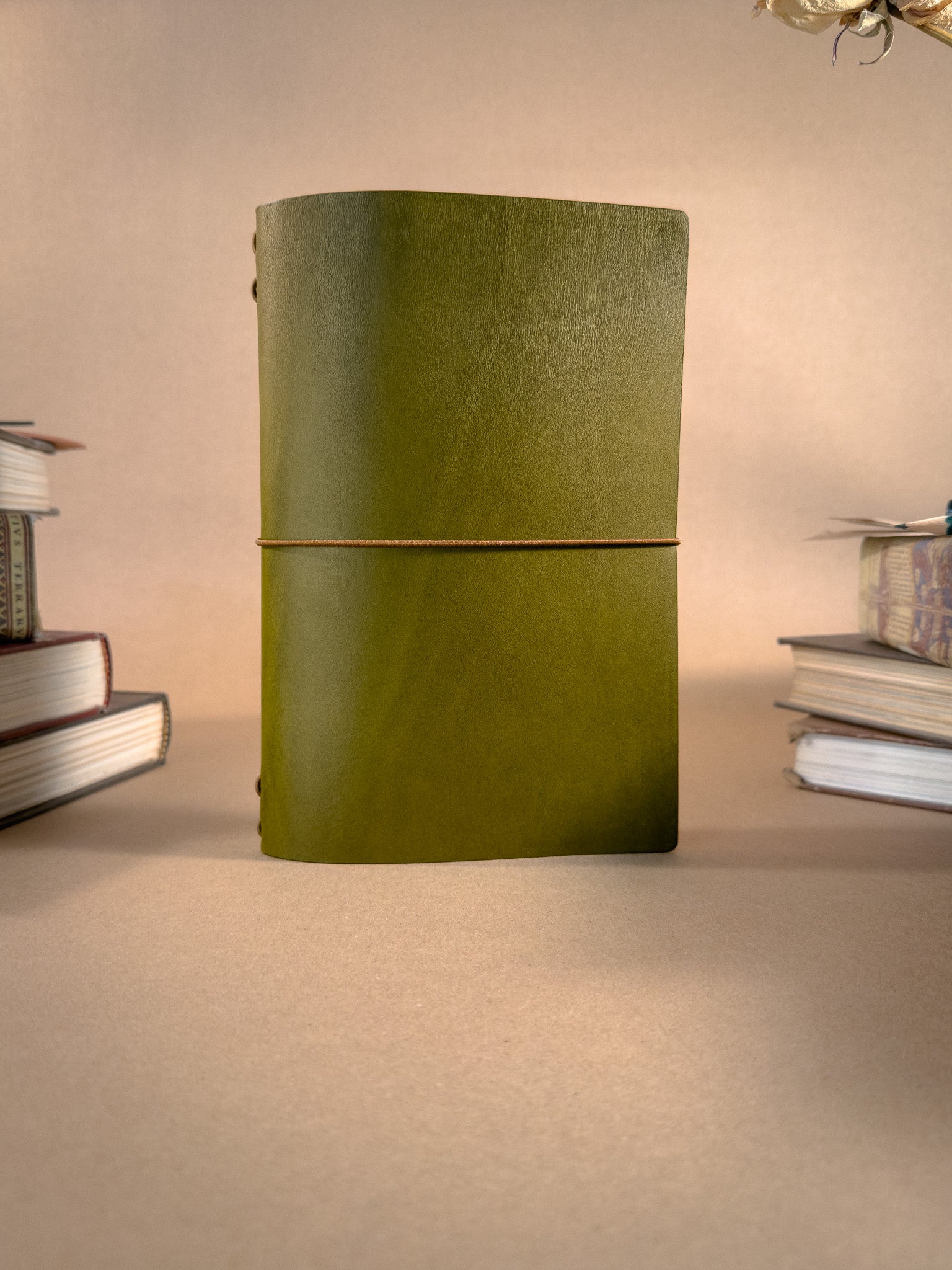 A Green book bag sized leather Journal on a beige backround