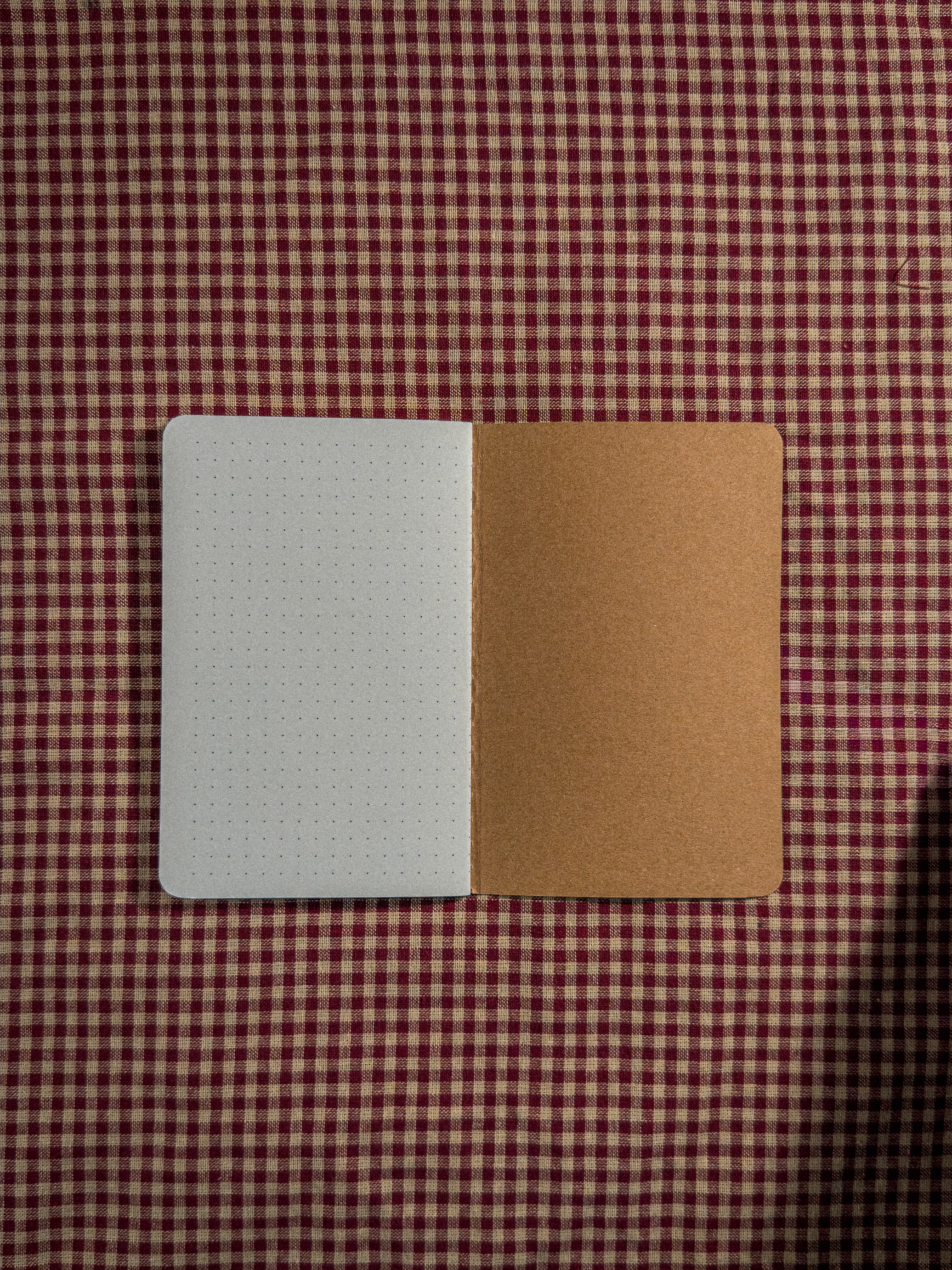 A small brown pocket sized paper notebook sized at 3" x 5.5" open flat