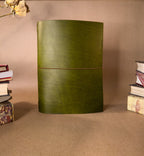 A Large Green desk sized leather Journal on a beige backround