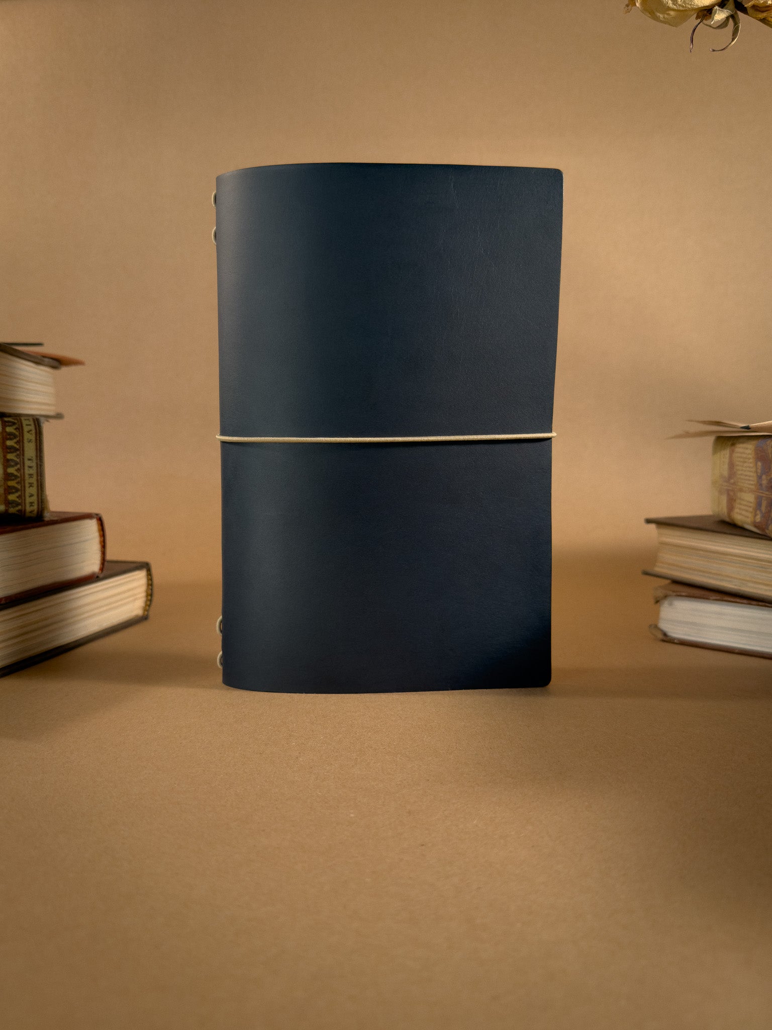 A Blue book bag sized leather Journal on a beige backround