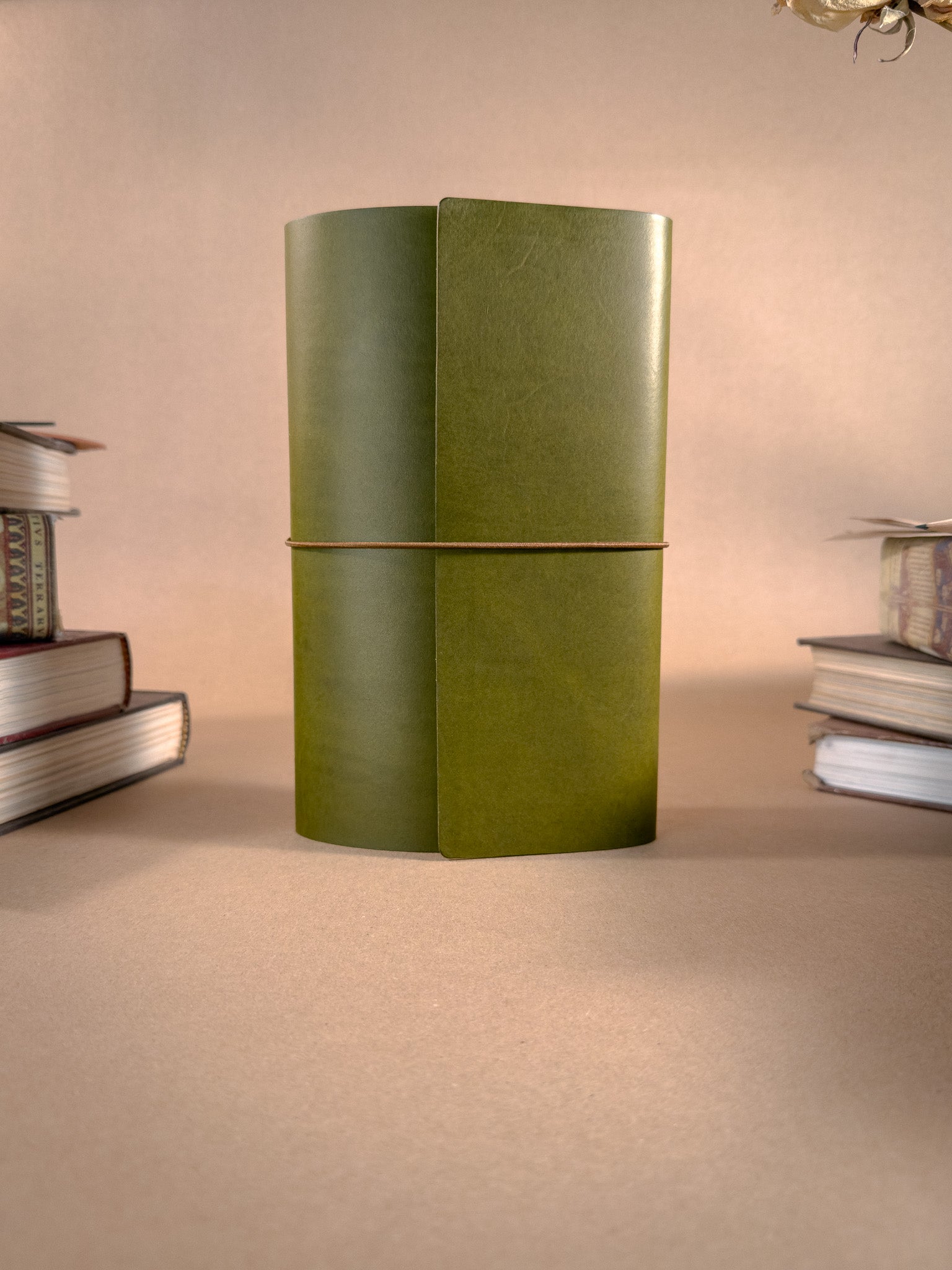 A tri-fold green leather journal on a beige background