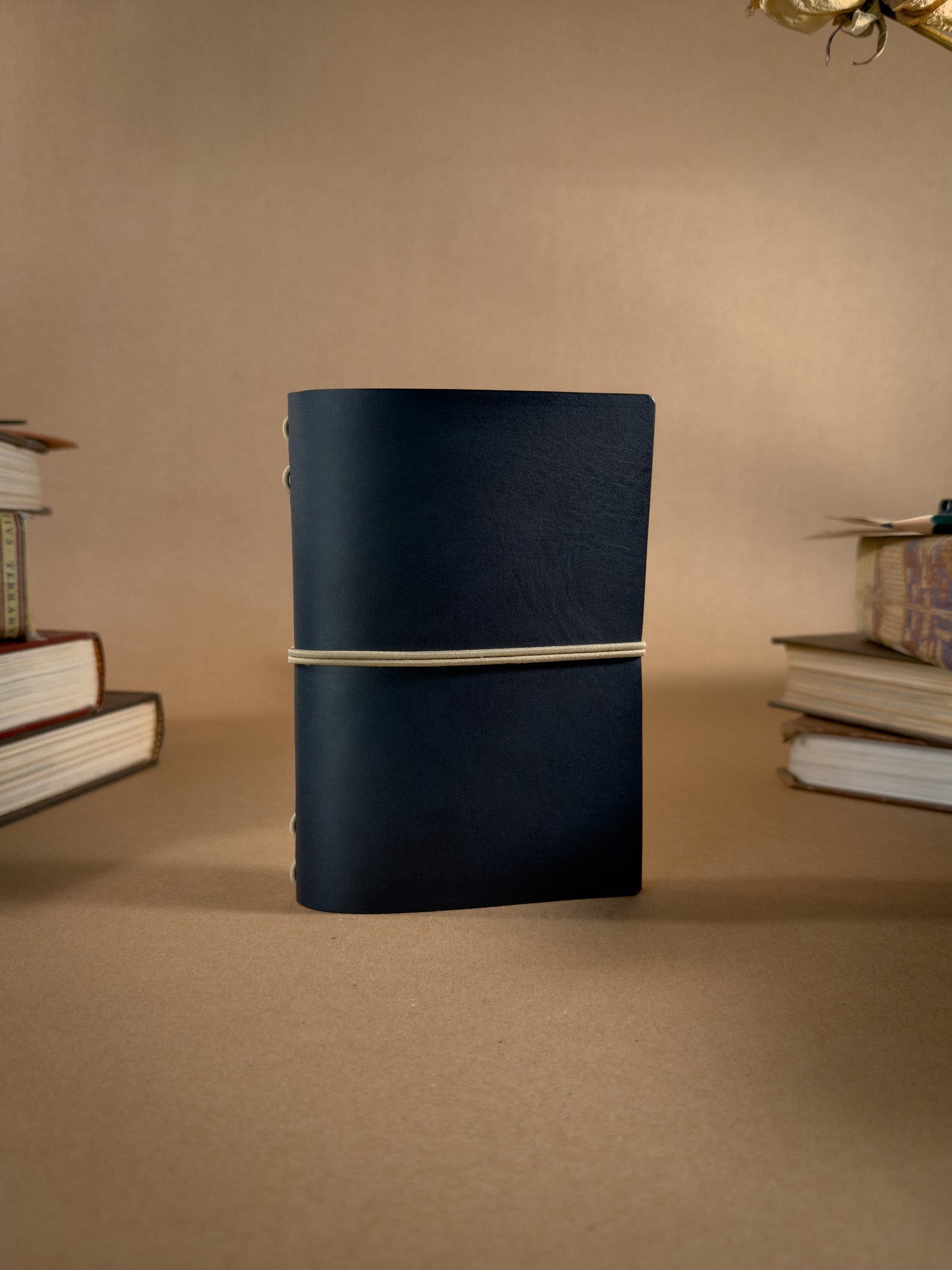 A blue pocket sized leather Journal on a beige backround